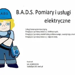 Karykatura elektryka w niebieskim kombinezonie i kasku z napisem B.A.D.S, z miernikiem elektrycznym przy pasku, obok tekst informujący o pomiarach i usługach elektrycznych, przeglądach instalacji...