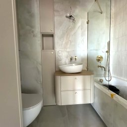 GES STUDIO Wykończenia wnętrz Sylwia i Wiktor Gęs - Nowoczesna łazienka z umywalką nablatową, kabiną prysznicową ze złotymi detalami i płytkami imitującymi marmur. Minimalistyczny design z elementami luksusu.