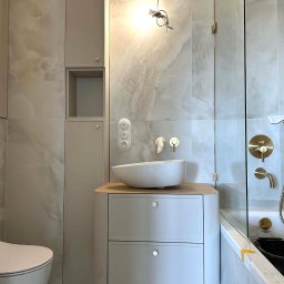 GES STUDIO Wykończenia wnętrz Sylwia i Wiktor Gęs - Elegancka łazienka w odcieniach szarości z umywalką nablatową, złotą armaturą i kabiną prysznicową. Widoczne płytki imitujące marmur i minimalistyczne szafki.
