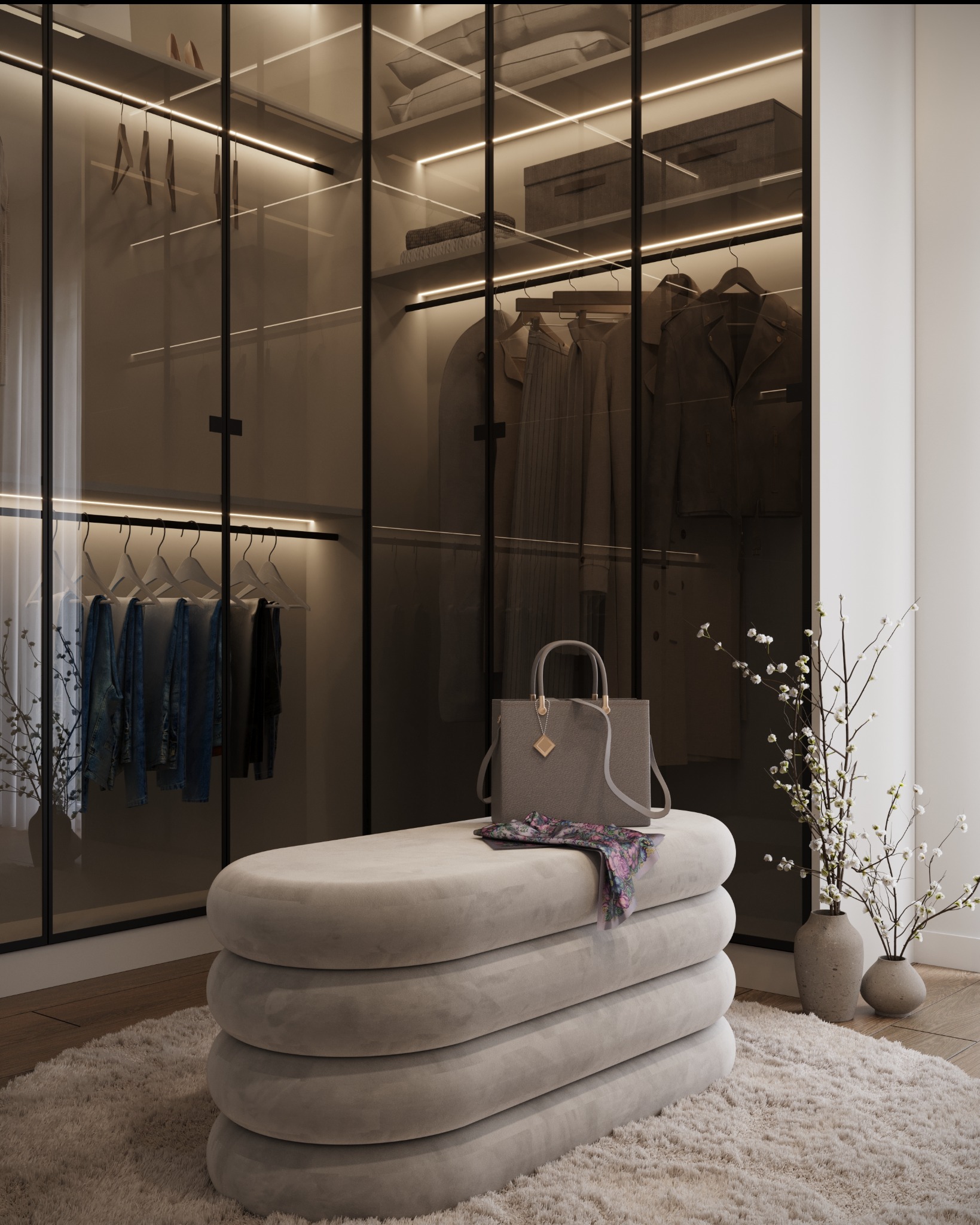 Nowoczesna garderoba z przesuwanymi szklanymi drzwiami, oświetleniem LED, ubraniami na wieszakach i półkach, z beżową pufą na pierwszym planie, na której leży torebka i apaszka w kwiaty.