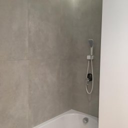 Odynets Aleksandr - Minimalistyczna łazienka z wanną, szarą, teksturowaną okładziną ścienną i subtelnym oświetleniem LED podsufitowym. Nowoczesna armatura.