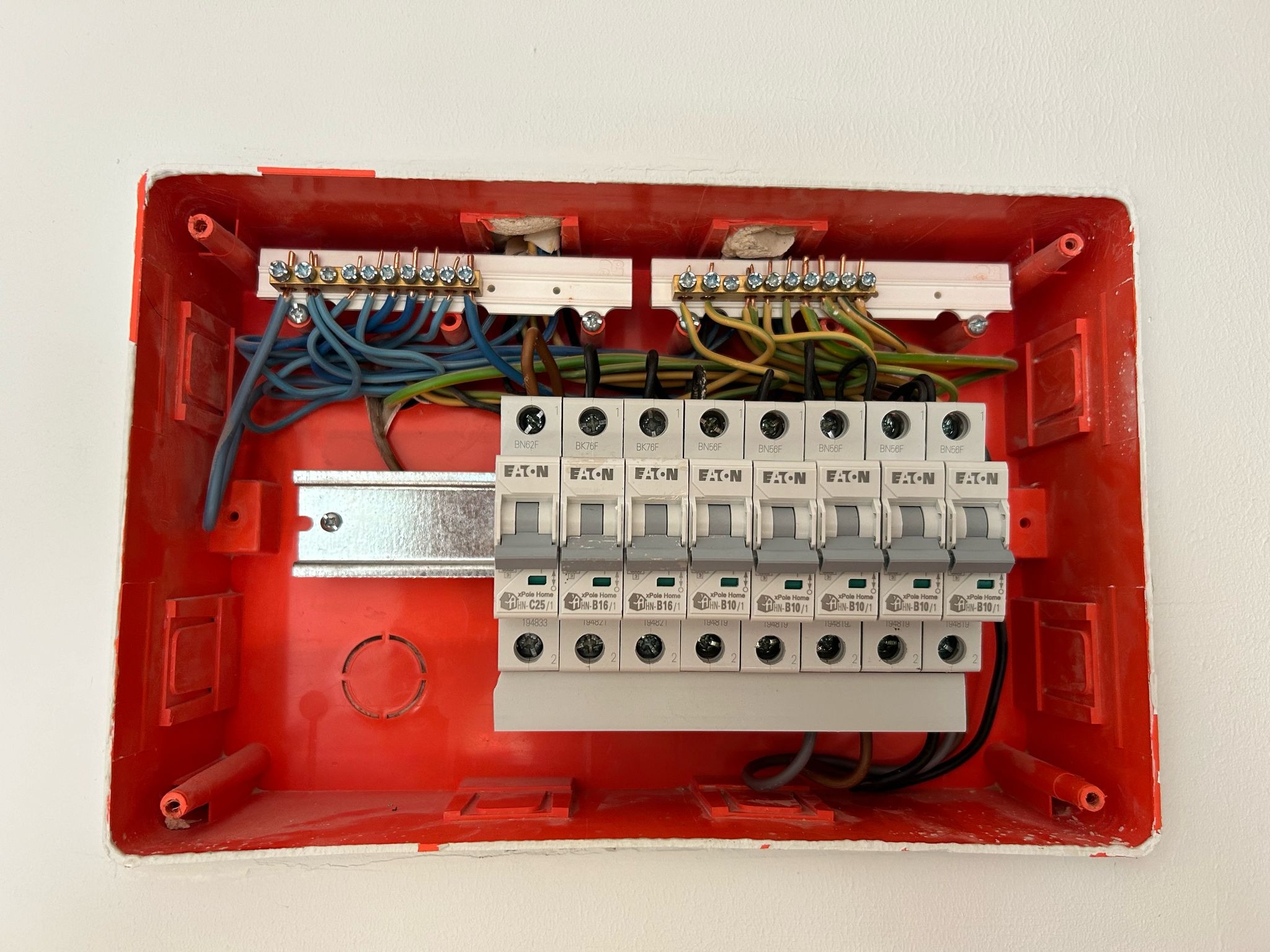 Rozdzielnica elektryczna Eaton z zainstalowanymi bezpiecznikami, widoczne przewody, instalacja w trakcie montażu w Węgorzynie, pomarańczowa obudowa.