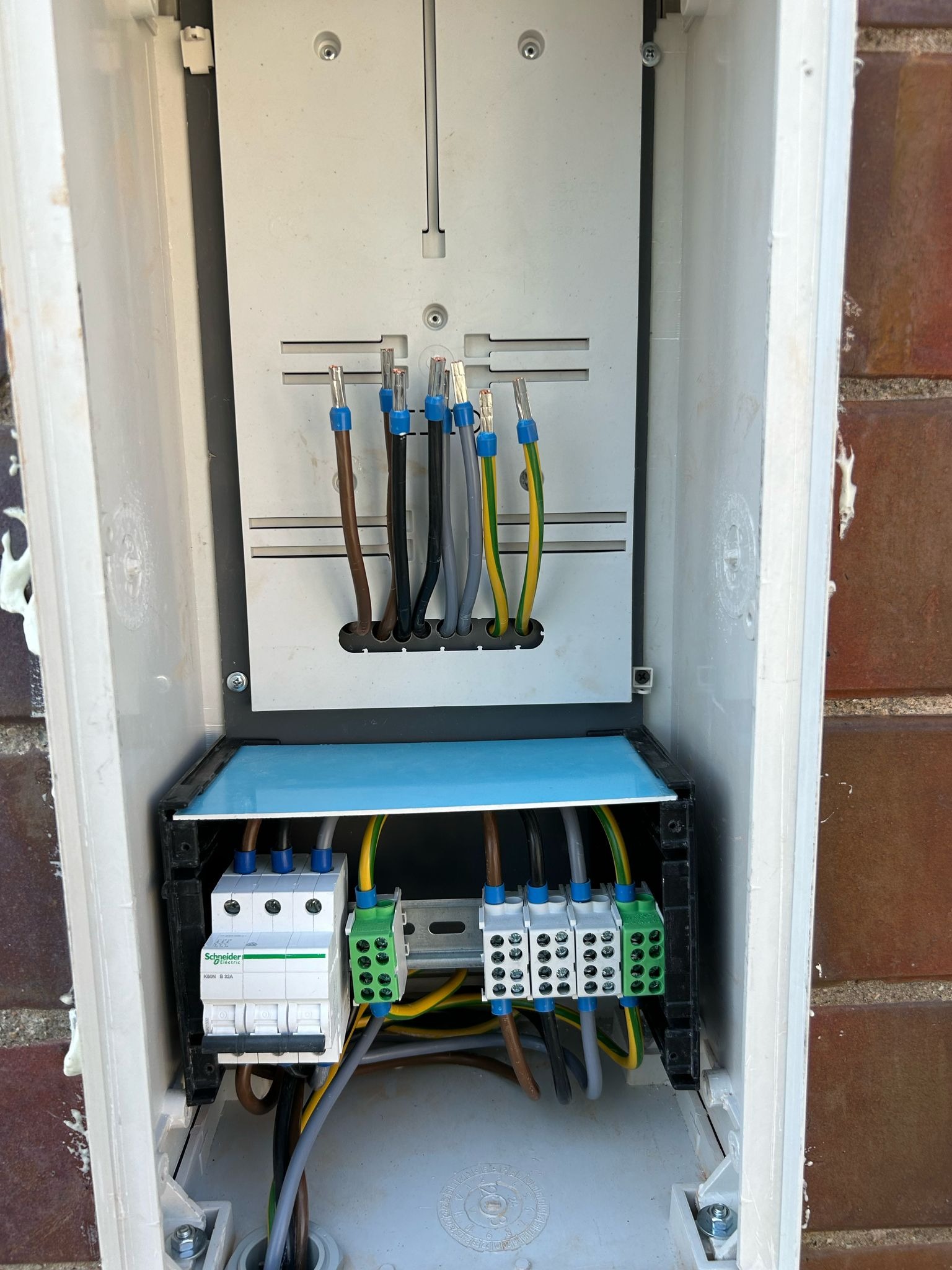 Wnętrze skrzynki elektrycznej z zamontowanymi bezpiecznikami i przewodami, widoczne złącza WAGO i zabezpieczenia Schneider Electric.