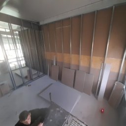 Kris-bau - Wnętrze w trakcie zabudowy ścian działowych z płyt kartonowo-gipsowych na metalowym stelażu, widok z góry na elementy konstrukcyjne i przygotowane płyty.