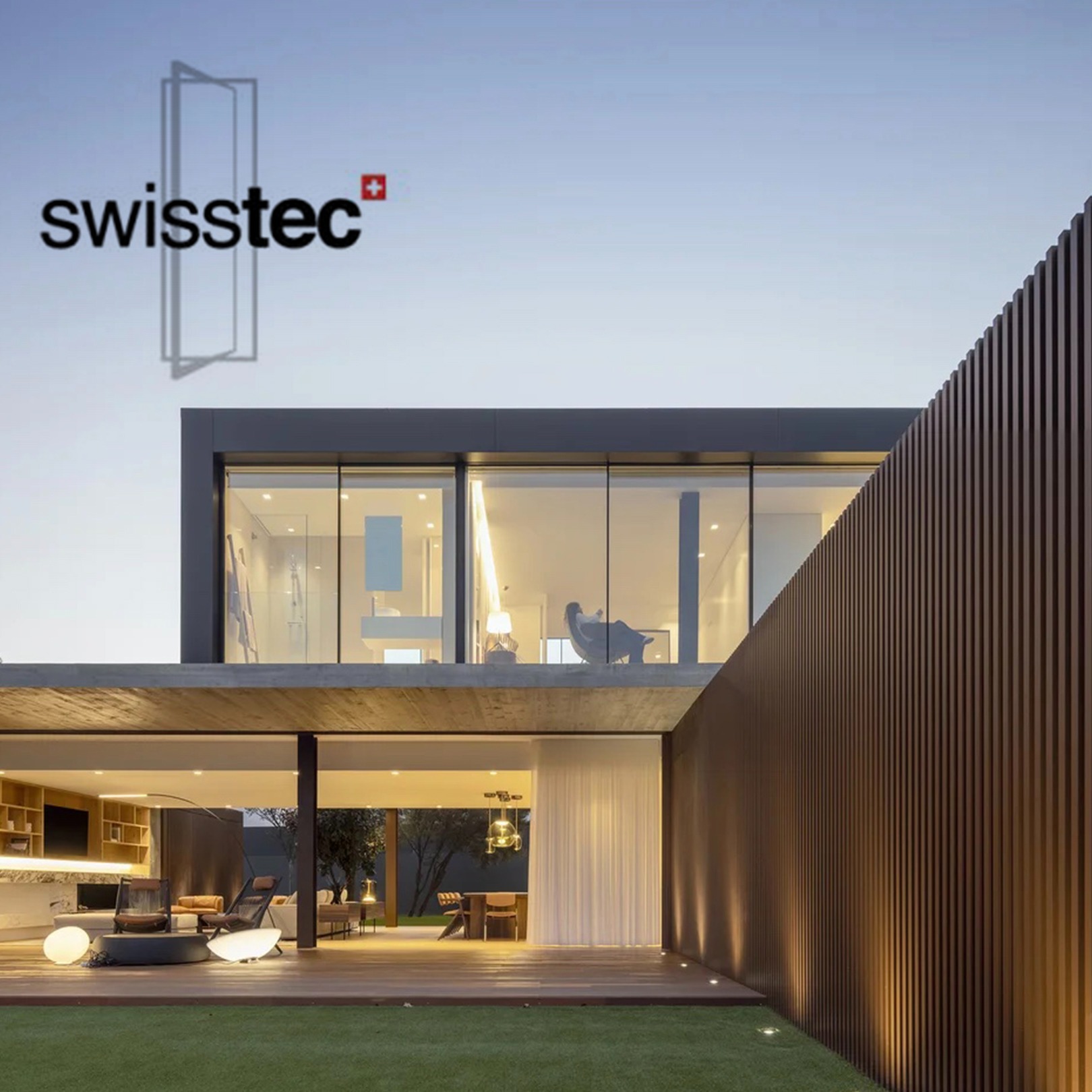 Nowoczesny dom z dużymi przeszkleniami i drewnianą fasadą, logo firmy widoczne na górze.