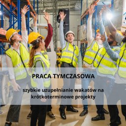 MAGNUM EUROPE SPÓŁKA Z OGRANICZONĄ ODPOWIEDZIALNOŚCIĄ - Grupa uśmiechniętych pracowników magazynu w żółtych kaskach i kamizelkach odblaskowych świętuje sukces z podniesionymi rękami na tle regałów magazynowych wypełnionych towarem.