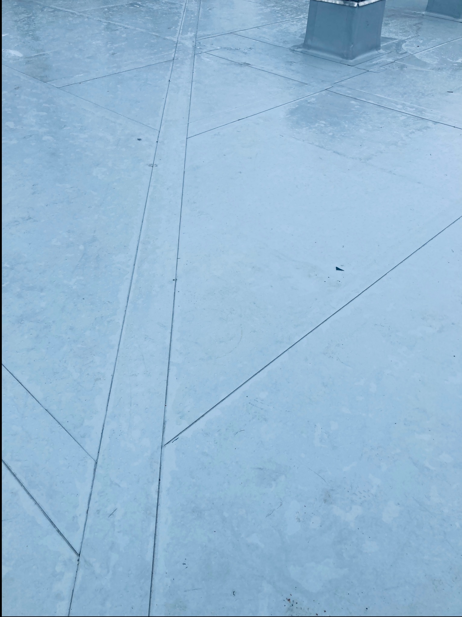 Płaski dach pokryty papą termozgrzewalną z widocznymi łączeniami i kominkiem wentylacyjnym w tle, świeżo po położeniu.