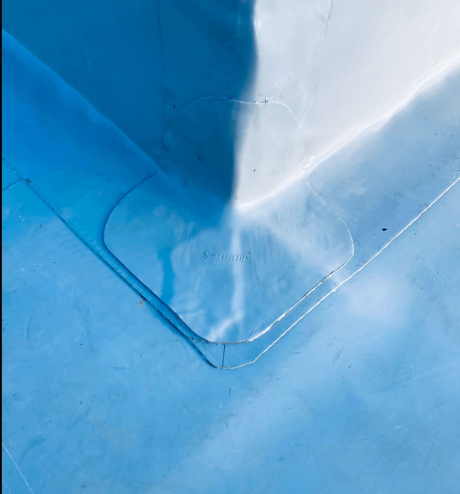 Fragment niebieskiego dachu z widocznym wytłoczonym logo producenta 'Sarnafil'.