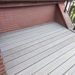 PHU KAROLINA SOKALSKA - Szare deski tarasowe ułożone na balkonie z ceglaną ścianą i metalową barierką, widoczne z góry pod kątem.