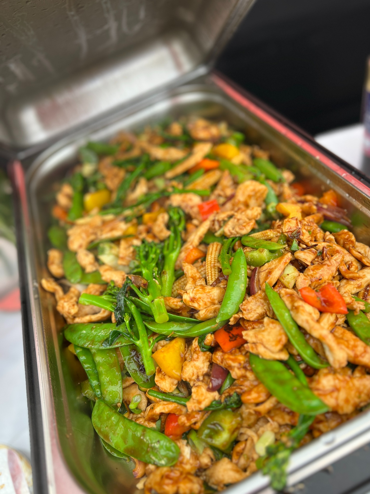 Stalowa bemar z podgrzewaną potrawą: kurczak stir-fry z brokułami, groszkiem cukrowym, papryką i kukurydzą baby.