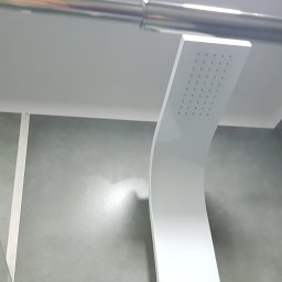 FIRMA HYLEK Jarosław Chylicki - Nowoczesna deszczownica w minimalistycznej łazience z szarymi ścianami i szklanym panelem.
