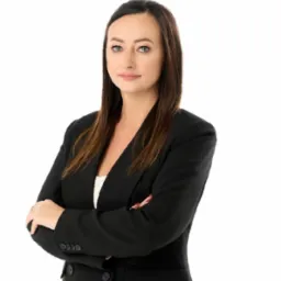 Portret kobiety w czarnym żakiecie, z założonymi rękami, na białym tle.