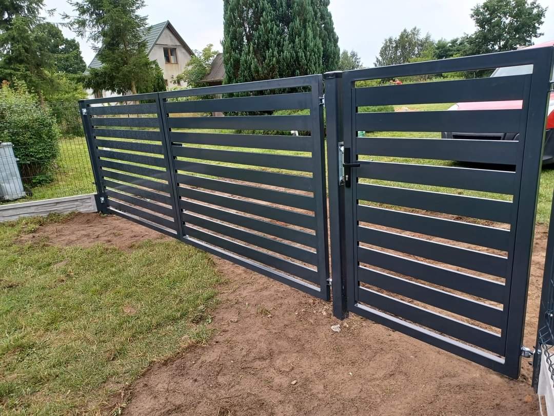 Nowoczesna, antracytowa brama wjazdowa z poziomymi panelami, widoczna na tle zielonego trawnika i domu.