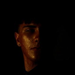 Olaf Chalecki - Portret mężczyzny z połową twarzy w cieniu i złotym brokatem na skórze, wykonany w Zielonej Górze.