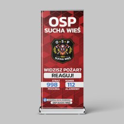 Mikołaj Stępień - Roll-up reklamowy z logo i hasłem OSP Sucha Wieś, informujący o numerach alarmowych straży pożarnej, z odnośnikiem do Facebooka.