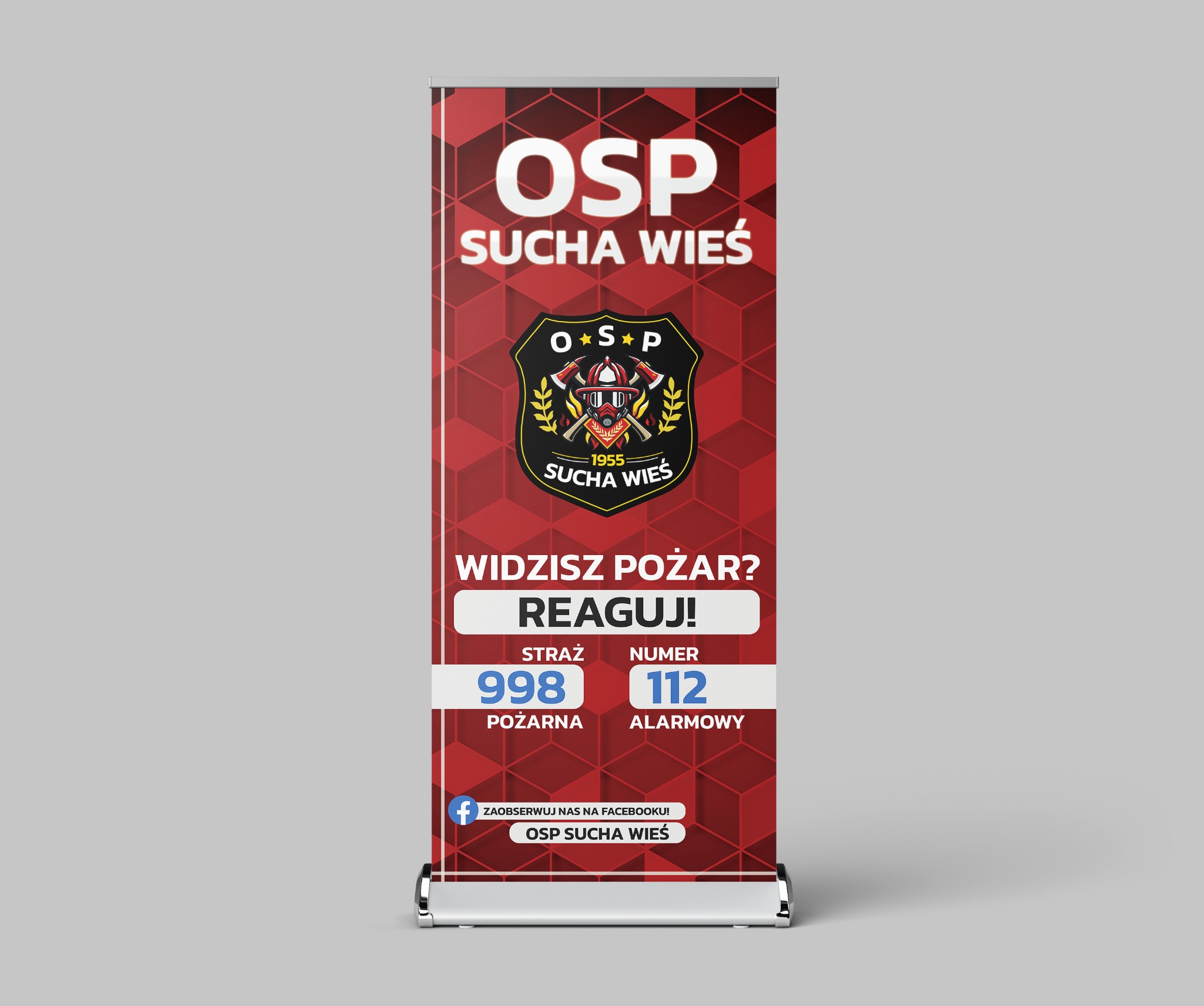 Roll-up reklamowy z logo i hasłem OSP Sucha Wieś, informujący o numerach alarmowych straży pożarnej, z odnośnikiem do Facebooka.