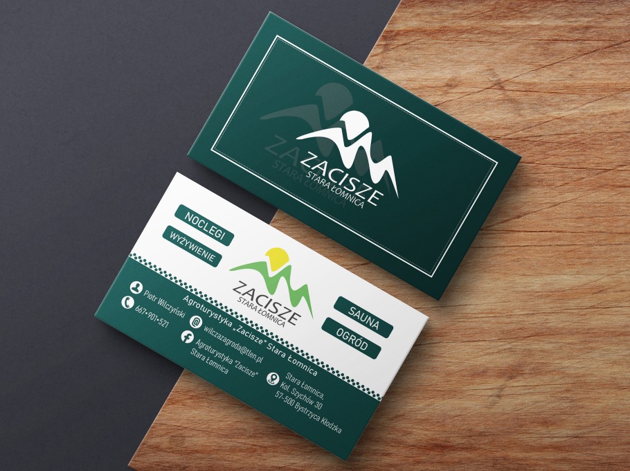 Dwie wizytówki agroturystyki 'Zacisze Stara Łomnica' na drewnianym i grafitowym tle. Jedna w kolorze ciemnozielonym z białym logo, druga biała z zielonymi elementami i danymi kontaktowymi.