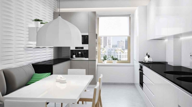 Jasna kuchnia z białymi frontami szafek, czarnym blatem, szarą tapicerowaną ławą i stołem, widok na miasto z okna.