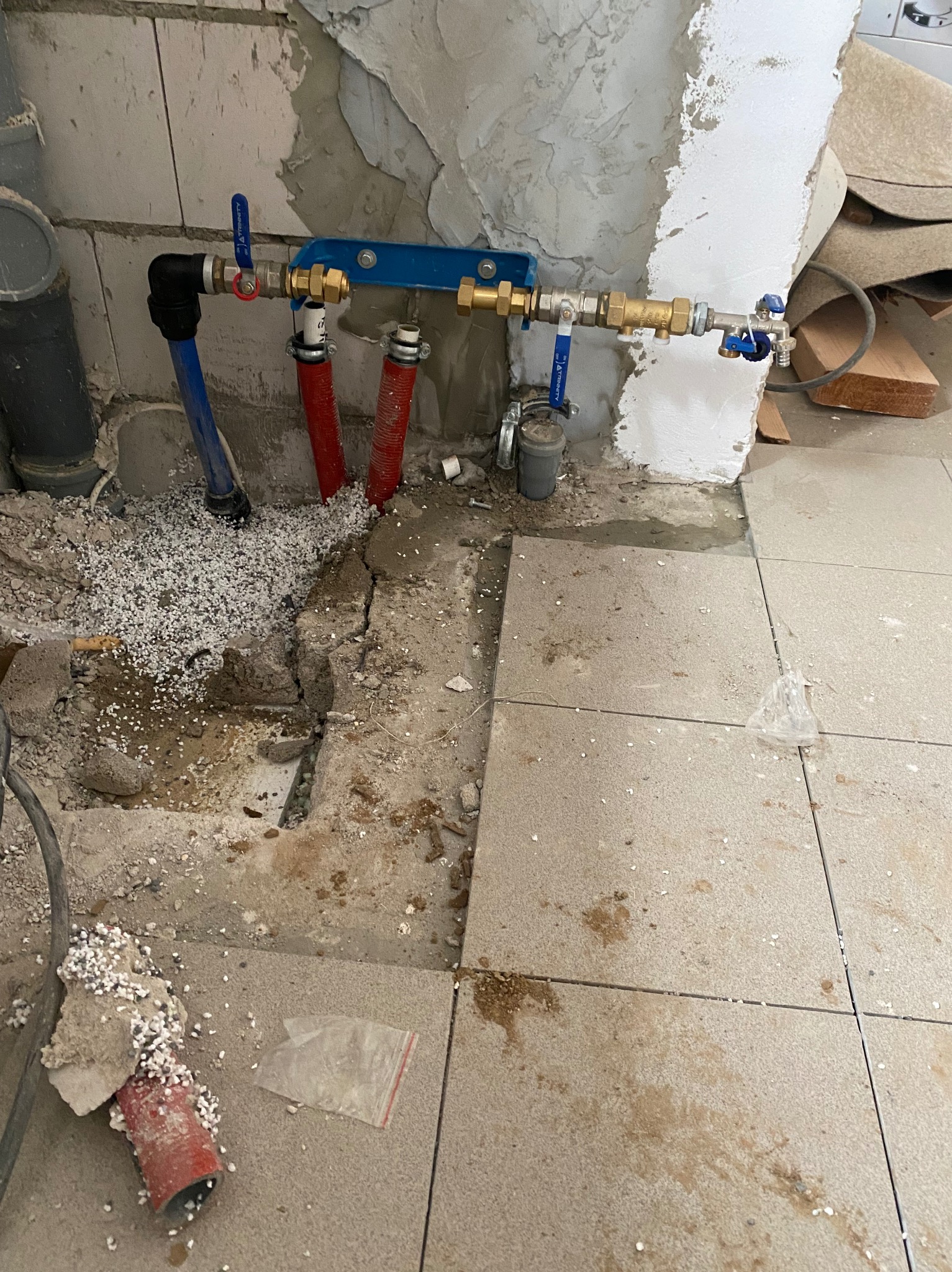 Fragment instalacji CO z rurami PEX w podłodze, widoczne przyłącza, zawory i izolacja, w trakcie prac wykończeniowych.