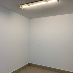 Szymon Lipka Usługi Budowlane - Pusty pokój po remoncie: gładkie, białe ściany, beżowa podłoga z płytek, listwy przypodłogowe i jarzeniówka na suficie.