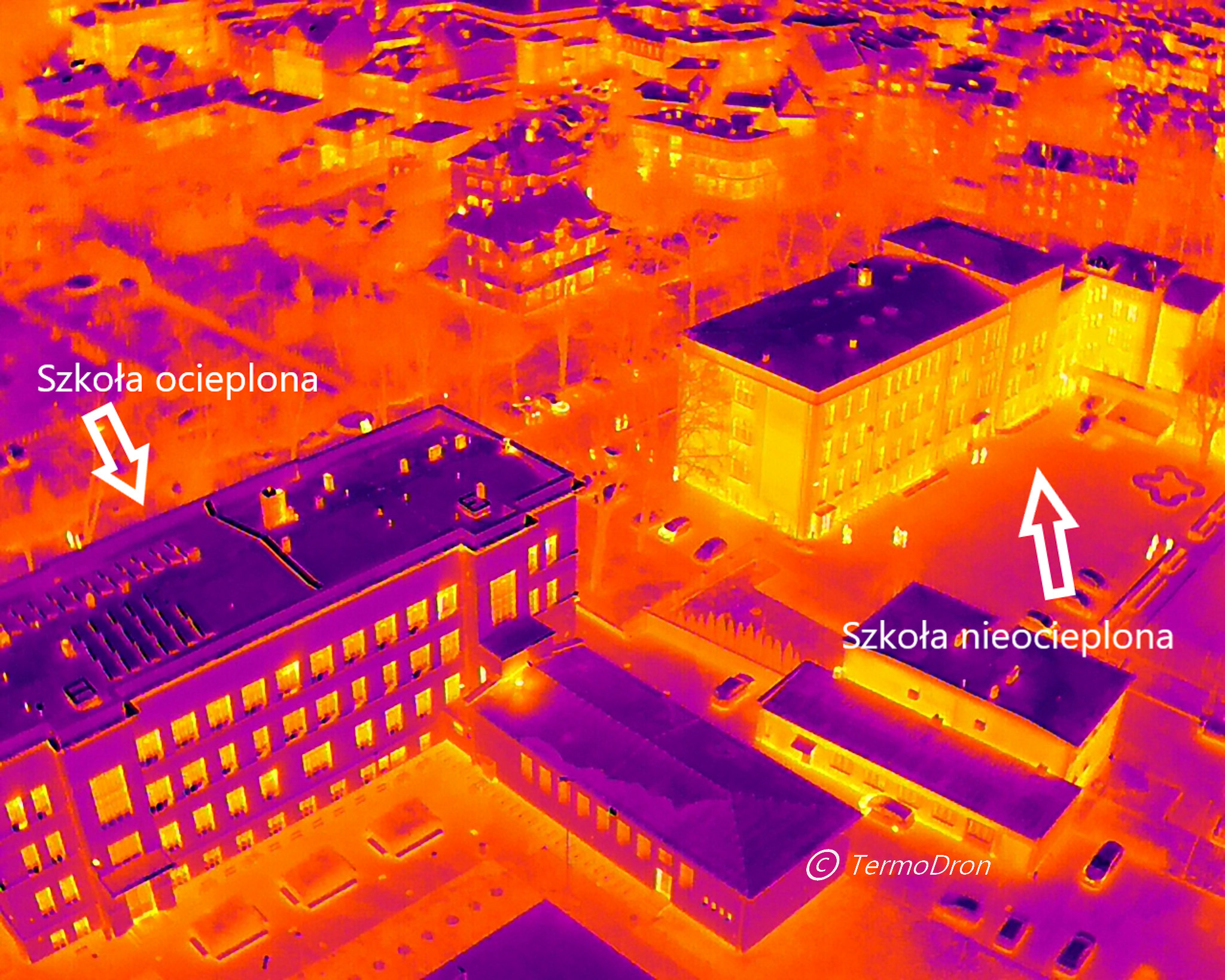Termowizyjne zdjęcie z lotu ptaka przedstawiające budynki szkolne; jeden budynek ocieplony, drugi nieocieplony, widoczne różnice temperatur w kolorach fioletu i pomarańczy.