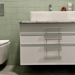 Pracownia m2 - Nowoczesna łazienka z wiszącą toaletą i szafką pod umywalkę z trzema szufladami, wykończona zielonymi płytkami o delikatnej fakturze.