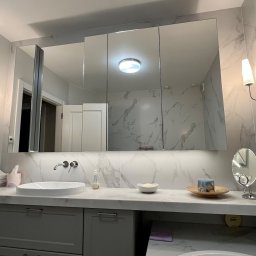 Pracownia m2 - Nowoczesna łazienka z marmurową ścianą, umywalką nablatową, podświetlanym lustrem w szafce i minimalistycznymi kinkietami