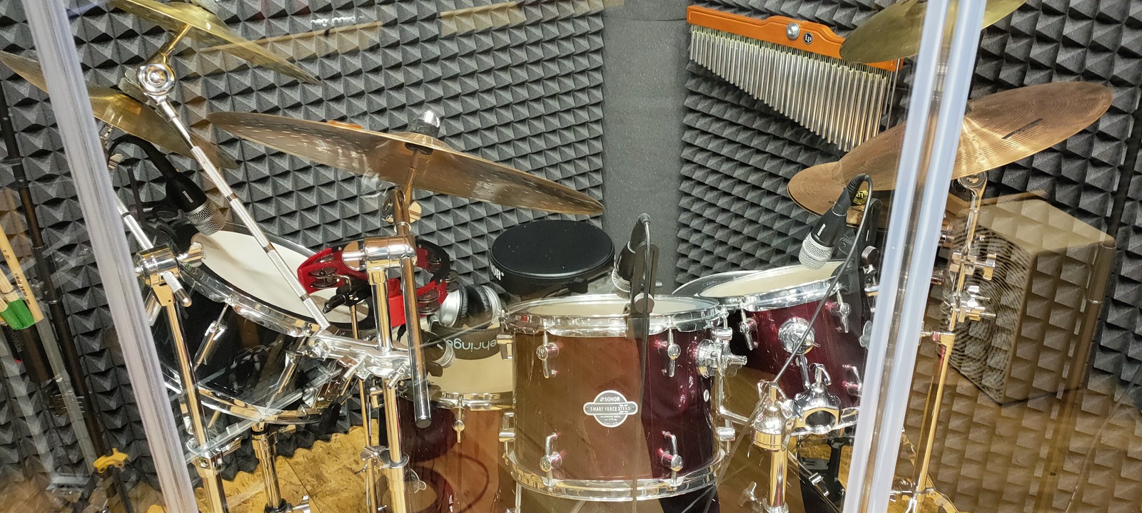 Zestaw perkusyjny marki Sonor w profesjonalnie wygłuszonym pomieszczeniu, z widocznymi mikrofonami i instrumentami perkusyjnymi.
