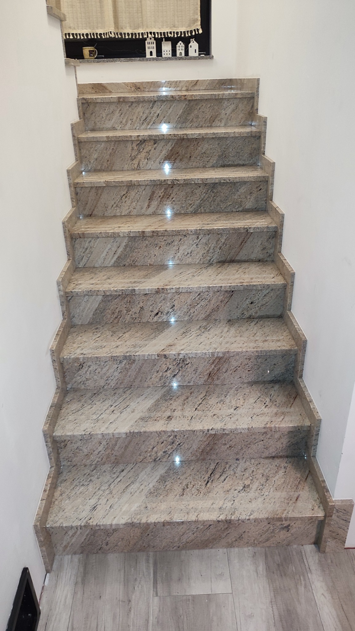 Kamienne schody wewnętrzne z subtelnym oświetleniem LED w stopniach, widok z góry, ukazujące precyzyjne wykonanie i estetyczne wykończenie.