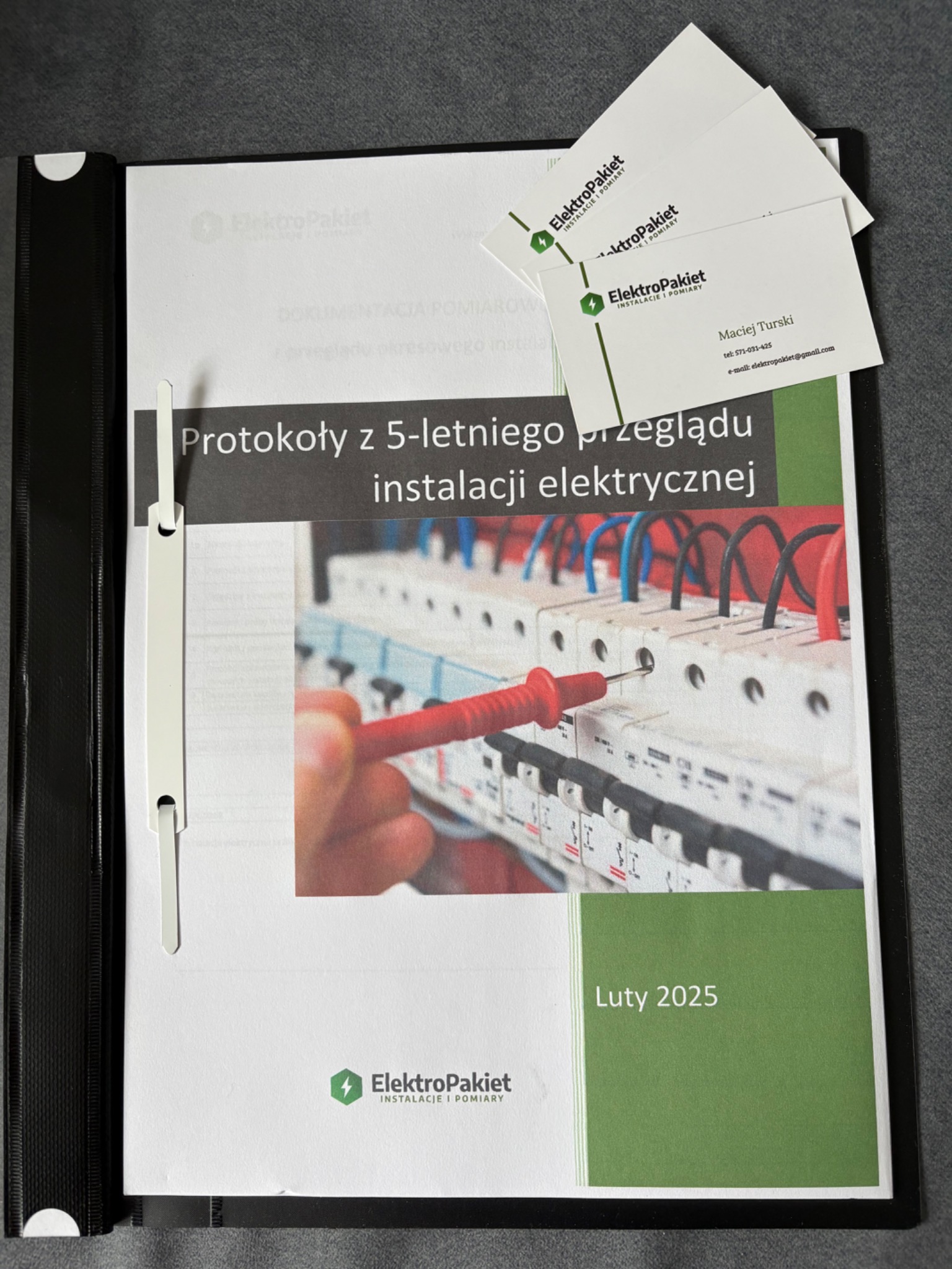 Dokumentacja z przeglądu instalacji elektrycznej w Łodzi, w czarnym segregatorze, z widocznym protokołem 5-letniego przeglądu, fragmentem schematu instalacji oraz wizytówkami firmy ElektroPakiet.
