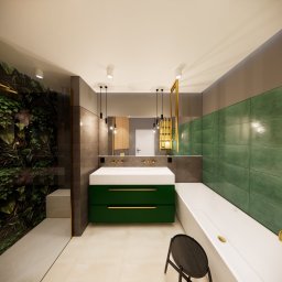 ART-DESIGN KAROL JURCZYK - Nowoczesna łazienka z zielonymi akcentami: roślinna ściana w kabinie prysznicowej, szafka pod umywalkę w kolorze butelkowej zieleni z złotymi uchwytami, biała wanna, szara ściana i złote elementy...