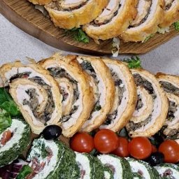 Piekielko u Agaty - Dekoracyjna taca z roladkami mięsnymi i warzywnymi, udekorowana pomidorkami koktajlowymi i oliwkami, prezentująca różnorodność smaków i estetyczne podanie.