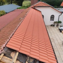arek.hamburg - Częściowo zdjęte stare dachówki i nowa, pomarańczowa dachówka ceramiczna na dachu domu jednorodzinnego z widoczną konstrukcją drewnianą i resztkami starej izolacji.