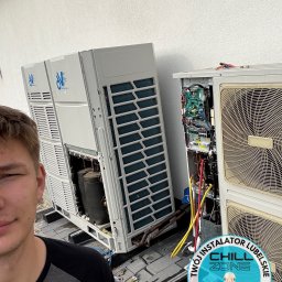 Chill Zone Mateusz Tomaszczuk - Serwisant klimatyzacji podczas naprawy dwóch dużych jednostek zewnętrznych. Widoczne narzędzia, otwarte obudowy i wewnętrzne komponenty. Logo firmy w rogu.