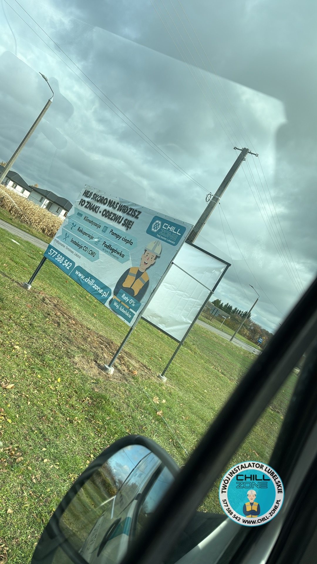 Billboard reklamowy firmy Chill Zone z Lubelskiego, oferującej klimatyzację, rekuperację, pompy ciepła i instalacje CO/CWU. Widok z wnętrza pojazdu, pochmurne niebo w tle.