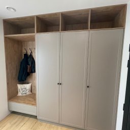 Rafał kloch - Zabudowa przedpokoju z szafą z szarymi frontami, otwartą wnęką z wieszakami i półką, oraz górnymi półkami z jasnego drewna.