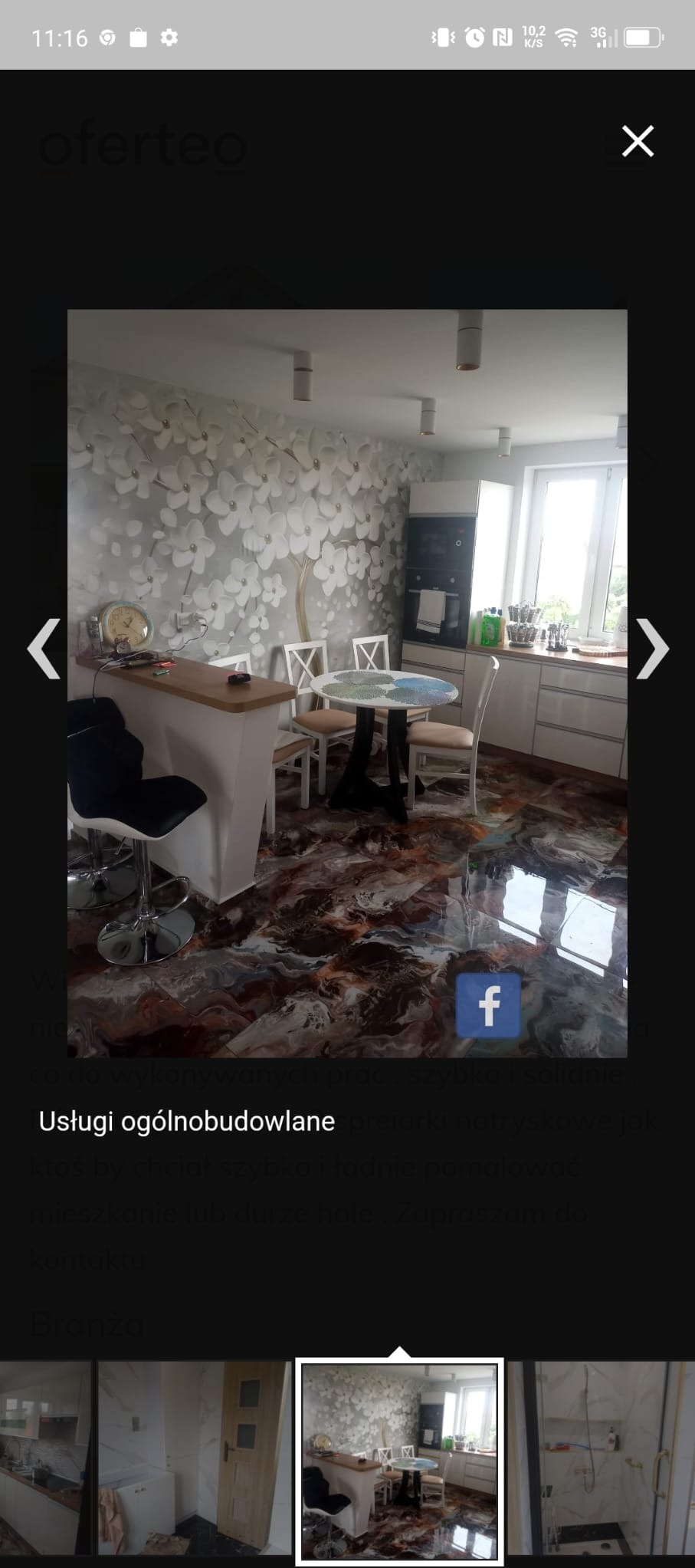 Wnętrze kuchni z oryginalną podłogą żywiczną w kolorach brązu i bieli, białe meble kuchenne, ściana z tapetą w kwiaty, stół z krzesłami i barek z hokerem.