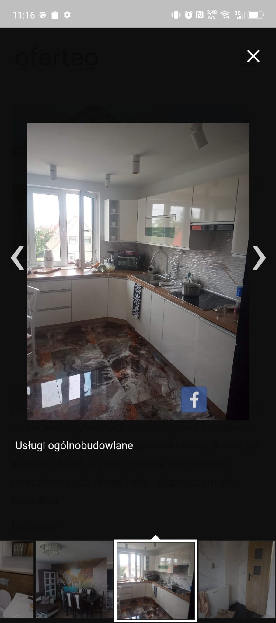 Nowoczesna kuchnia z białymi szafkami, drewnianym blatem i podłogą imitującą marmur, widziana z perspektywy wnętrza, z oknem w tle.