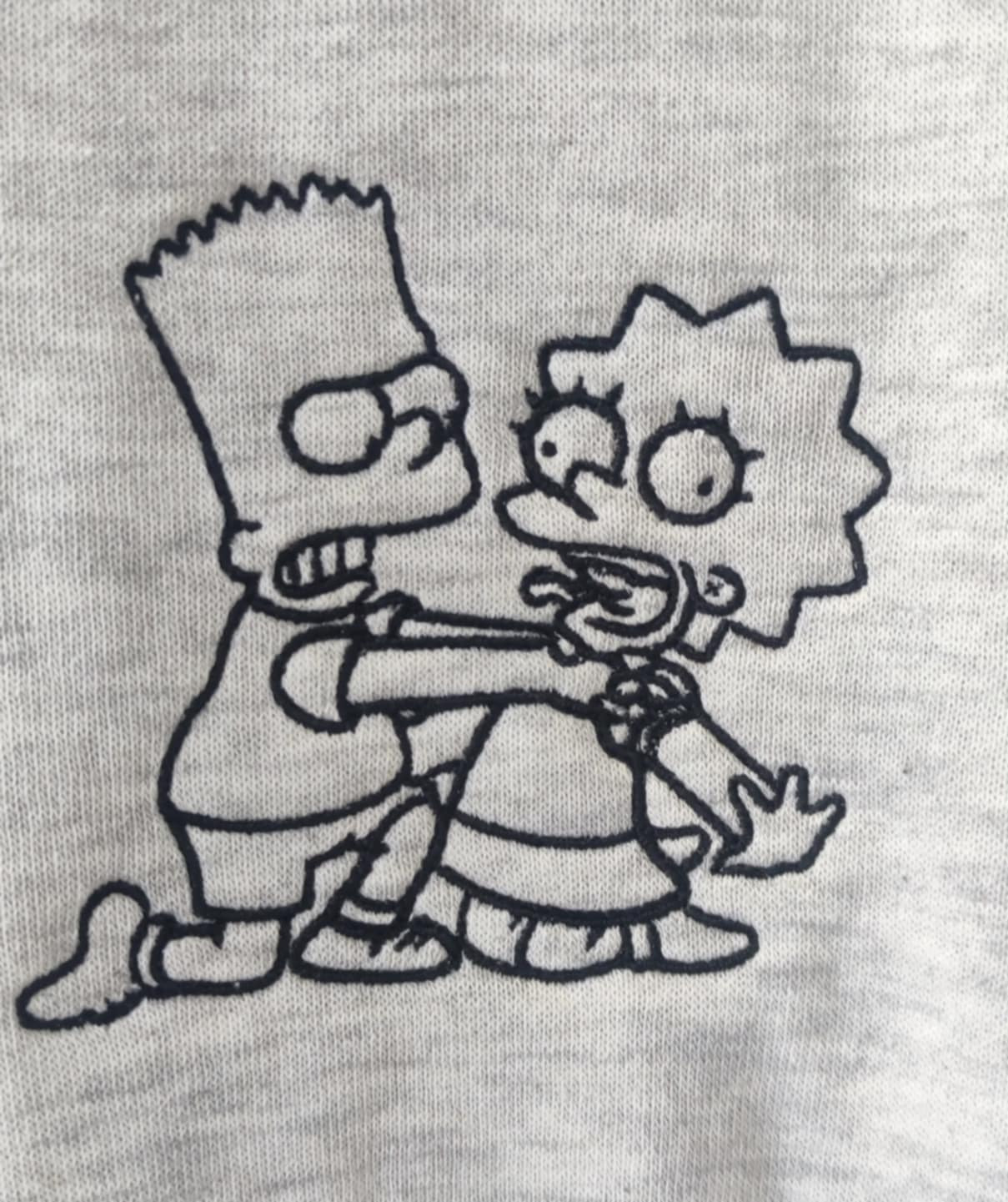 Szara koszulka z wyhaftowaną sceną z Simpsonów, przedstawiającą Barta duszącego Lisę, wykonana czarną nicią.