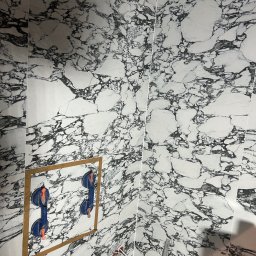 Serhii Horodetskyi - Montaż płytek imitujących marmur na ścianie we Wrocławiu, widoczne przyssawki do płytek i fragment instalacji.