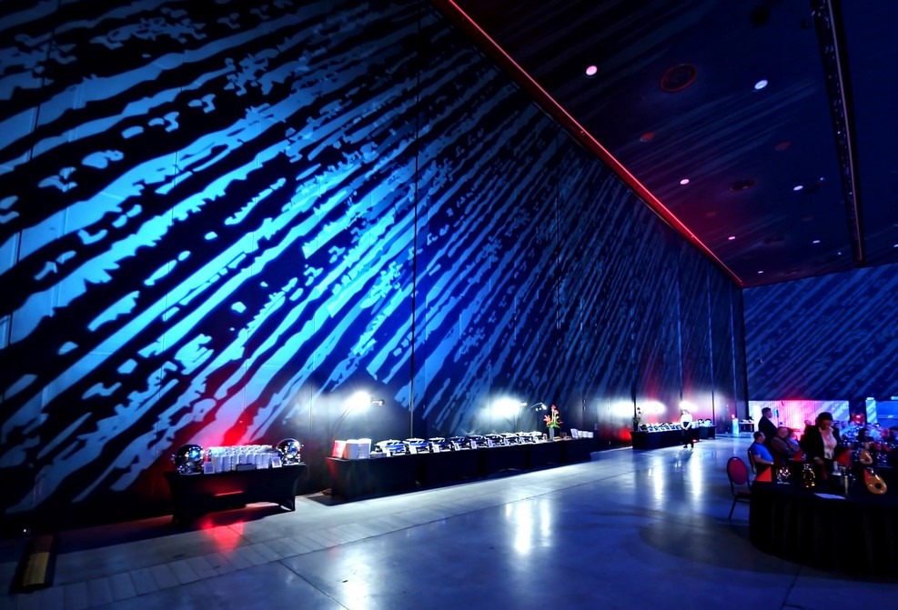 Oświetlenie dekoracyjne ścian sali bankietowej w Piekary Śląskie, z bufetem i gośćmi w tle. Dynamiczne, niebieskie wzory świetlne tworzą unikalny klimat imprezy.