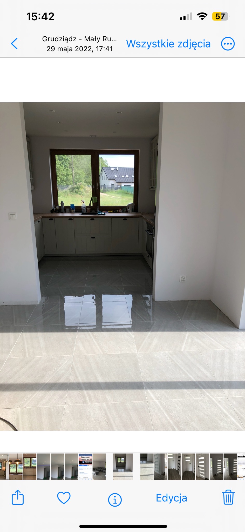 Jasna kuchnia z szarymi płytkami podłogowymi, widokiem na zieleń przez okno. Świeżo wyremontowane wnętrze, minimalistyczny styl.