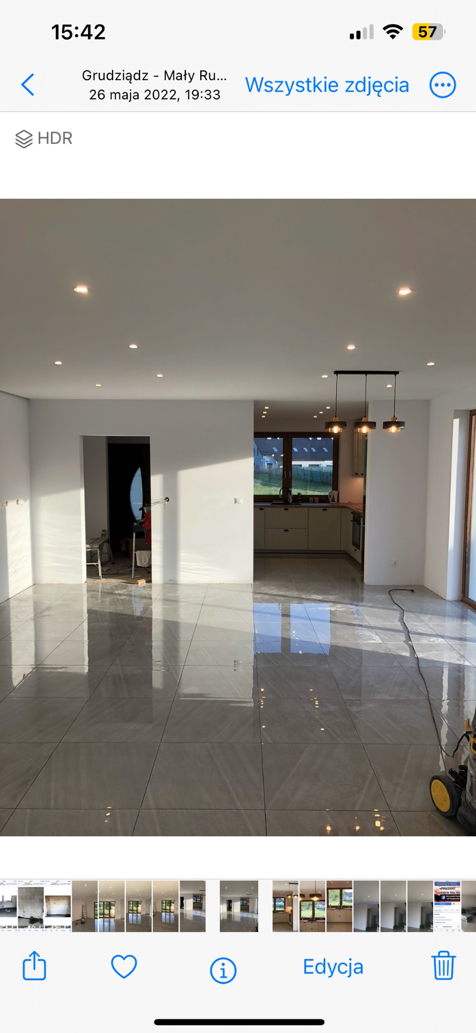 Jasne, przestronne wnętrze z nową, błyszczącą szarą podłogą z płytek. Widok na kuchnię i drzwi przesuwne. Świeżo po remoncie, gotowe do umeblowania.