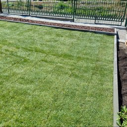 GREEN MASTER MYKHAILO BURDOVSKYI - Świeżo ułożony trawnik z rolki, obrzeża z kostki, widoczny fragment rabaty z przygotowaną ziemią pod nasadzenia, paleta i kosz na śmieci w tle.