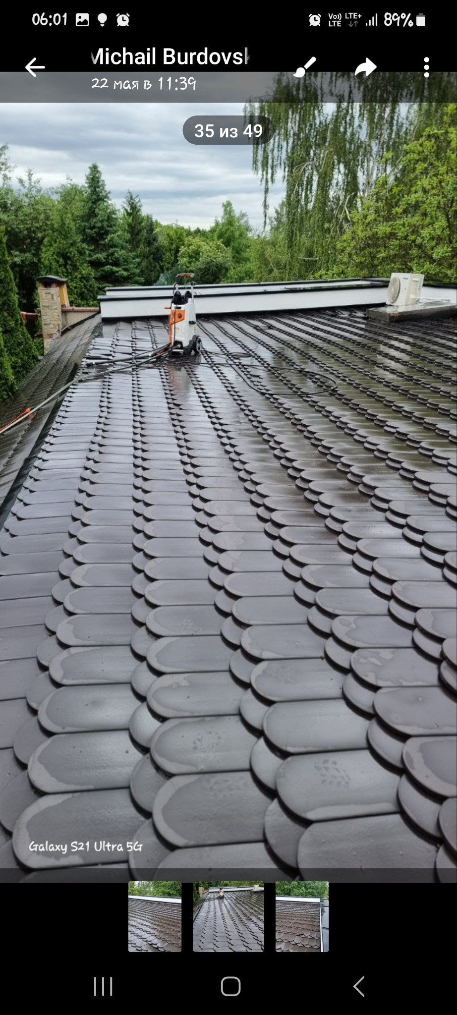 Czyszczenie dachu z dachówki bitumicznej za pomocą myjki ciśnieniowej, widoczne ślady czyszczenia, w tle drzewa i komin.