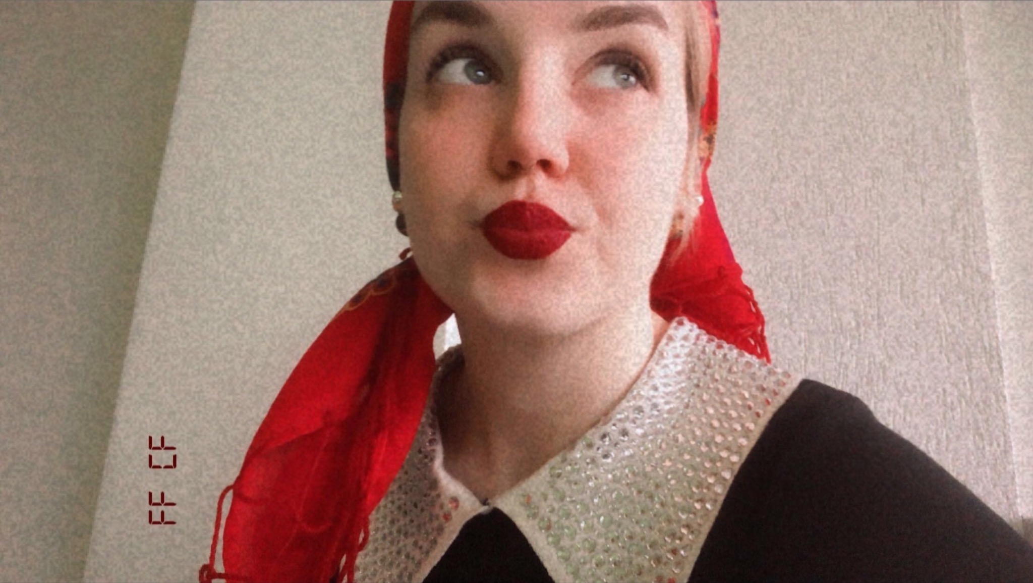 Portret kobiety z czerwonymi ustami, w czerwonej chuście na głowie i ozdobnym kołnierzykiem, spoglądającej w górę, z filtrem ziarnistym.