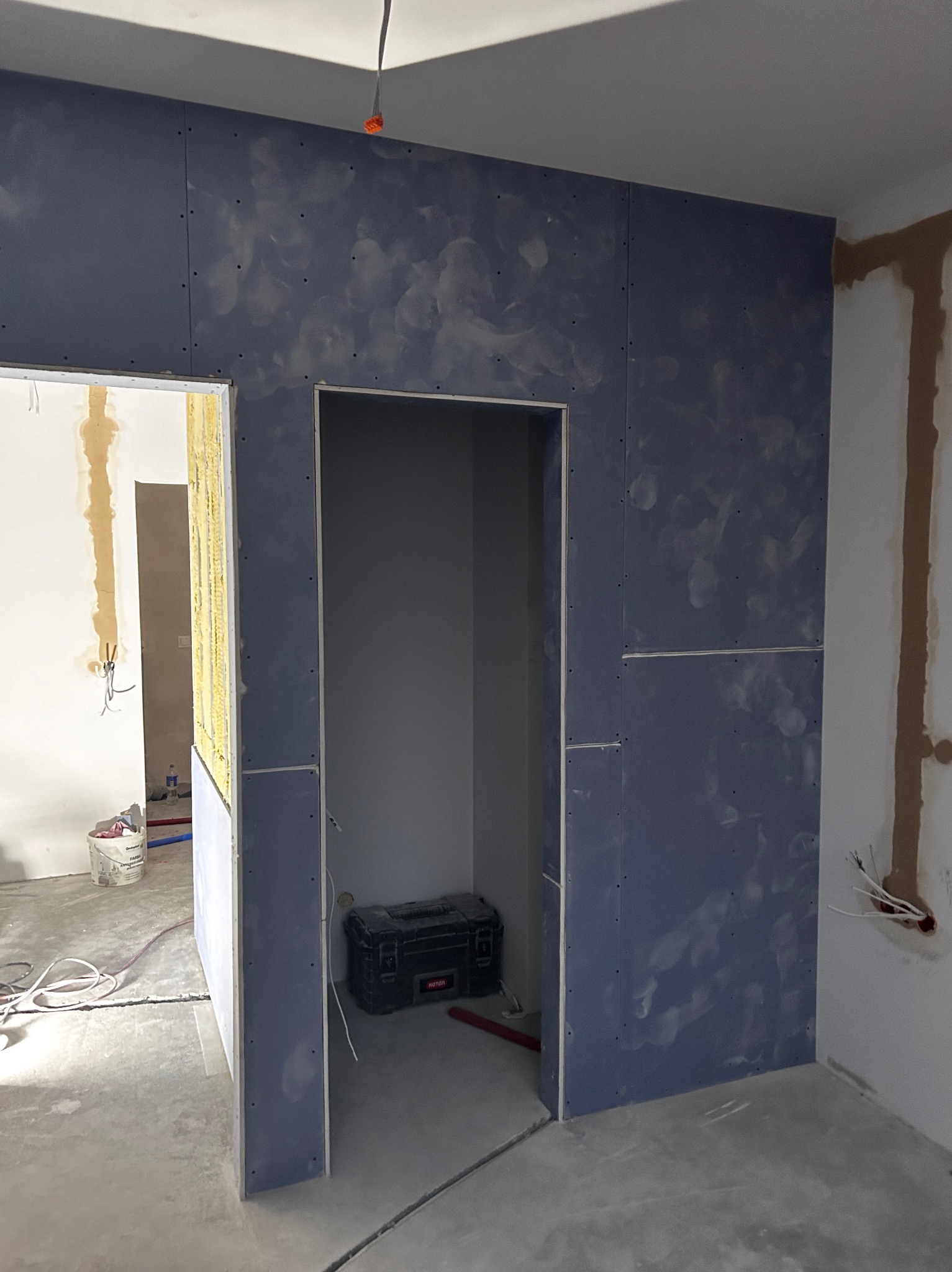 Montaż niebieskich płyt gipsowo-kartonowych, widoczne ślady po szpachlowaniu, przygotowanie do dalszych prac wykończeniowych w nowym pomieszczeniu.