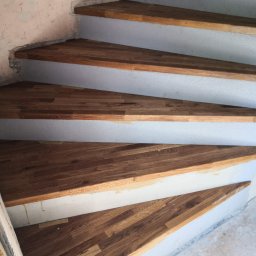 Tomasz Wiatrowski - Drewniane stopnie schodów spiralnych w trakcie montażu, widoczne surowe ściany i szpary do wypełnienia.