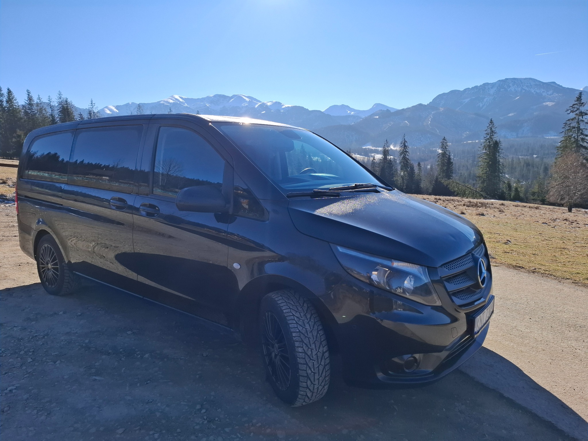 Czarny van Mercedes-Benz Vito z przyciemnianymi szybami na tle górskiego krajobrazu w słoneczny dzień.