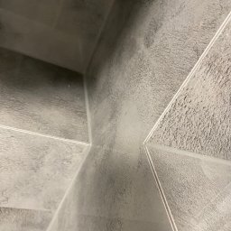 Marek Jarosz ZAKŁAD REMONTOWO-BUDOWLANY - Szare, matowe płytki ceramiczne ułożone pod kątem, z widocznymi fugami. Minimalistyczny design, surowa estetyka, bliski kadr na fragment ściany lub podłogi.